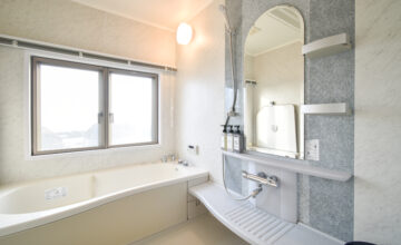 広々とした浴室も清潔感のある白で統一。ミラーの形がワンポイント。