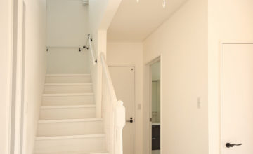 【玄関ホール、階段】玄関をあけてすぐ目の前は真っ白な壁と床。 照明はシャンデリア調のペンダントライトです。 使うのがなかなか難しい白の内装が上手くハマってます！
